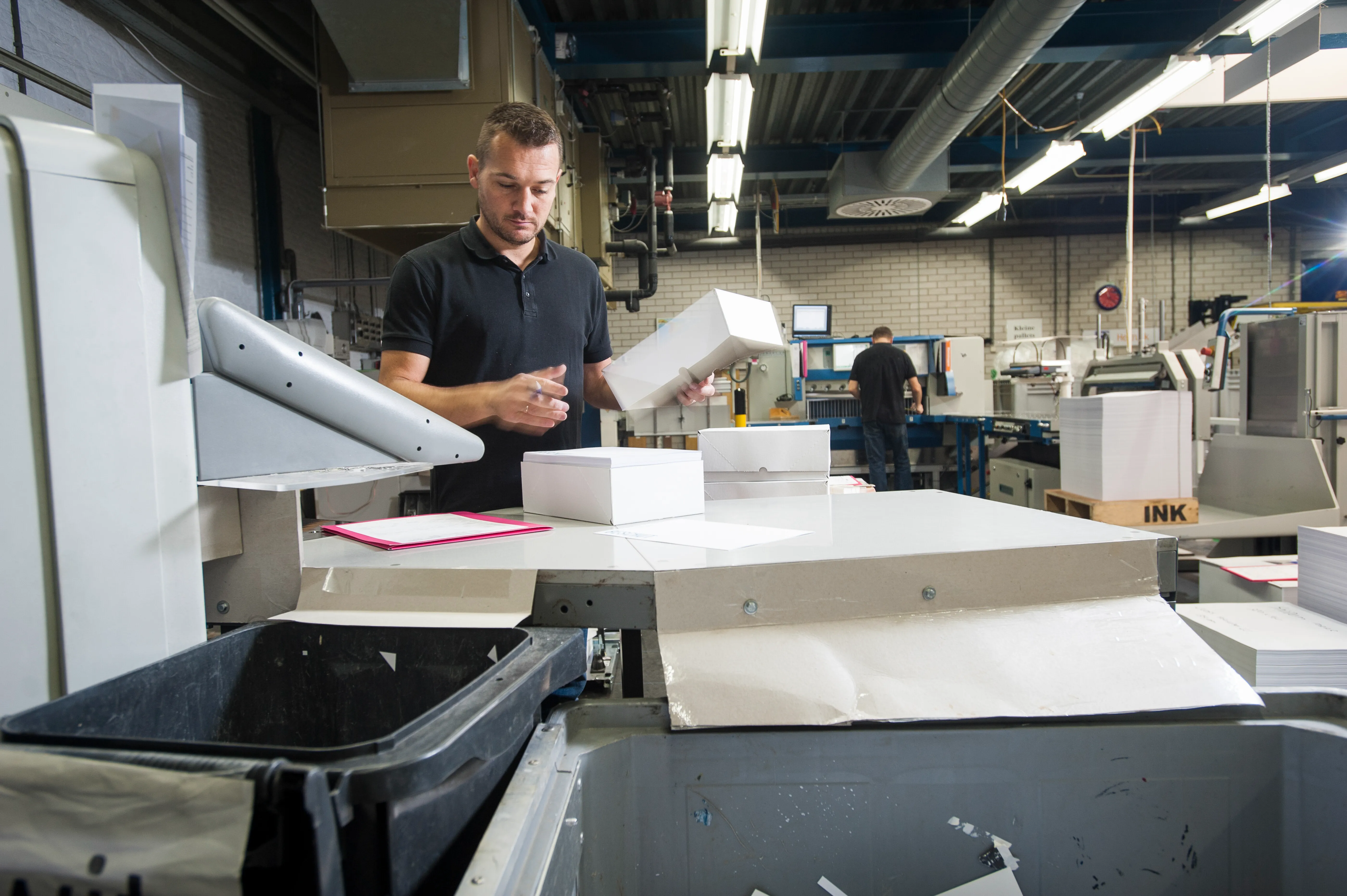 Fotografía de un hombre que conoce qué es una imprenta, organizando papel de impresión
